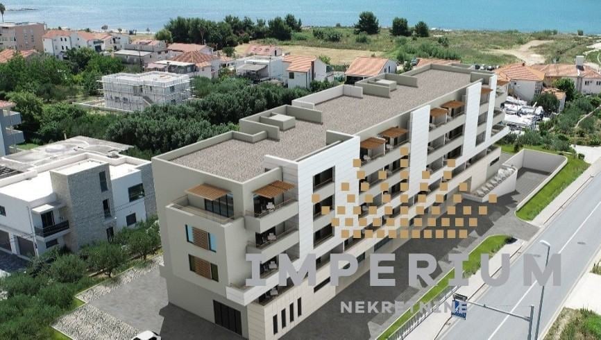 Modern multi-story residential apartment building under construction in suburban area with surrounding homes and clear sky