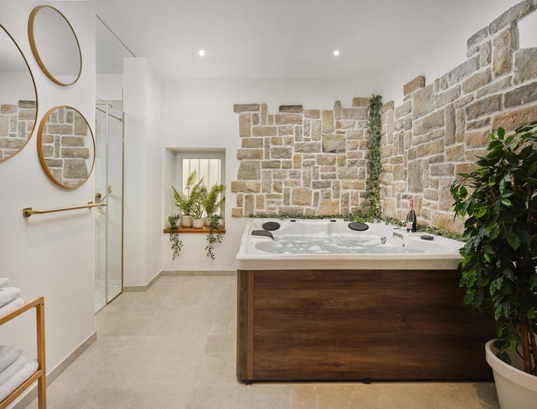 Modern spa bathroom with wooden hot tub, brick accent wall, decorative mirrors, and potted plants