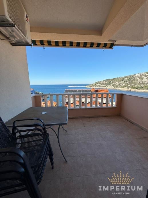 Balcony terrace with black furniture overlooking Mediterranean coastline and hillside with clear blue sky
