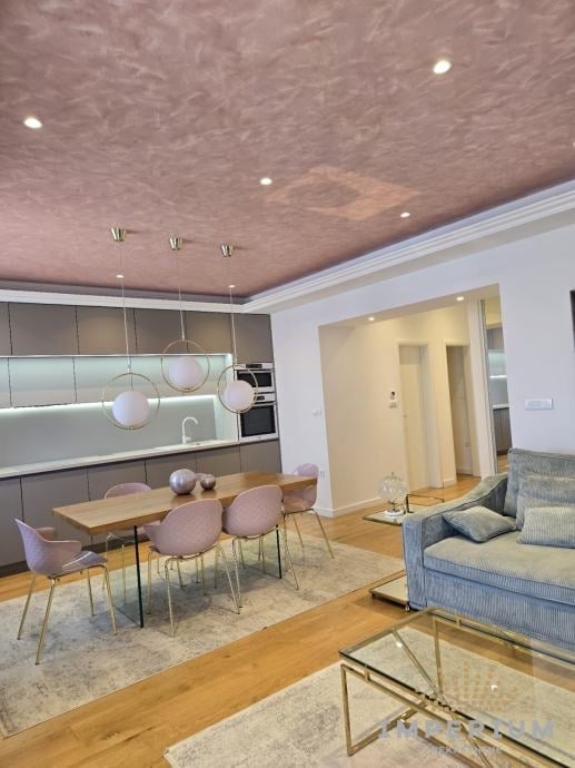Modern open-plan apartment interior with dining area, kitchen, and living space featuring contemporary furniture and pendant lights