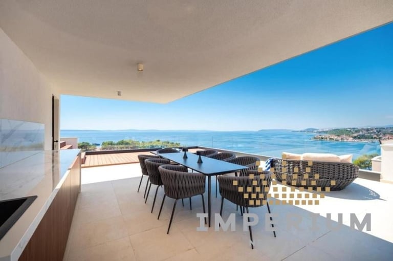 Modern balcony with dining table overlooking Mediterranean coastline and blue sea