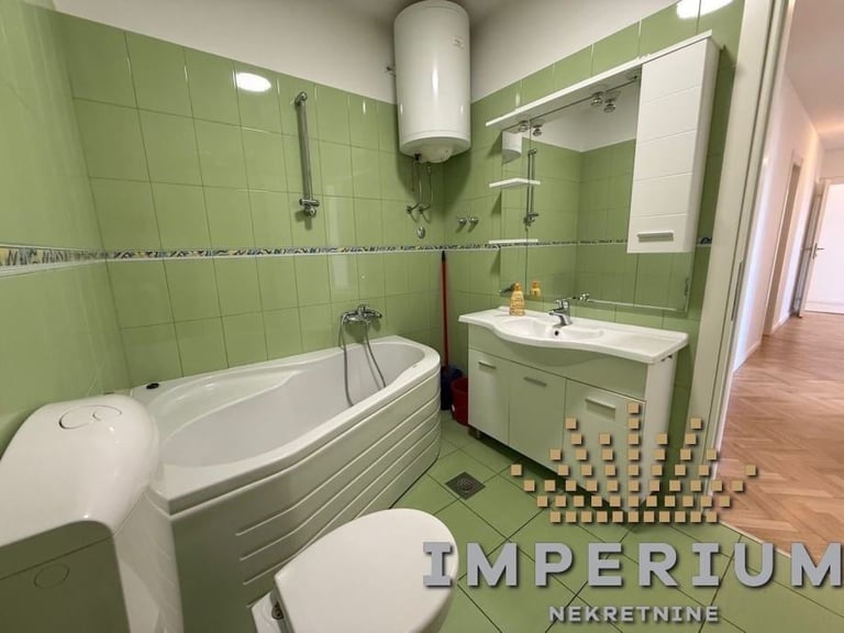 Bright green bathroom with bathtub, toilet, sink vanity, mirror, and water heater. Decorative candles displayed on floor.