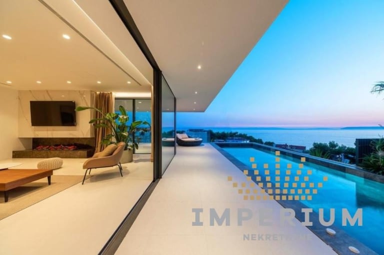 Modern luxury beachfront villa with open-concept living area, infinity pool, and panoramic ocean sunset views