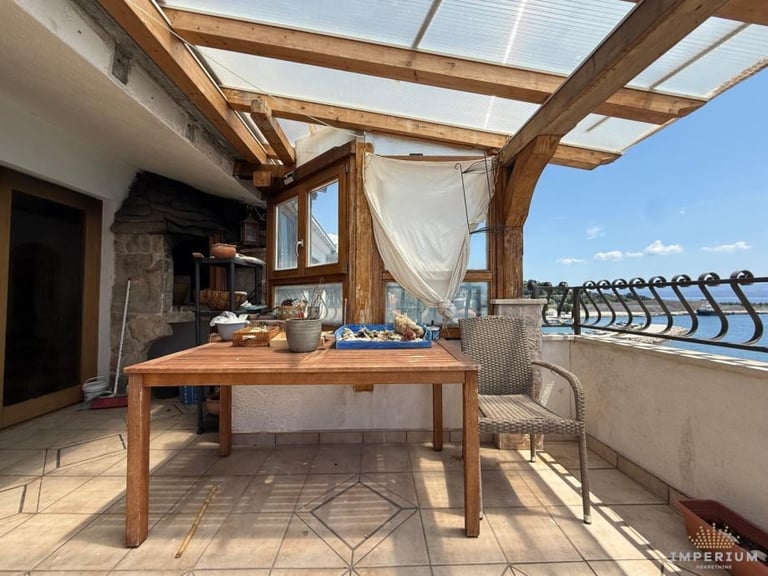 Sunny rooftop terrace with wooden pergola, dining table, lounge chairs, and city views
