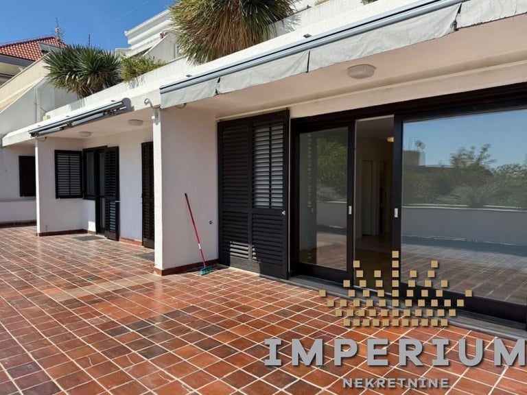 Modern white villa with terracotta tile patio, palm trees, and sliding glass doors overlooking a pool area