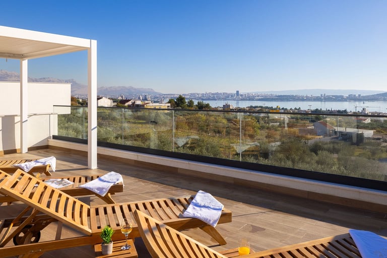 Modern rooftop deck with wooden lounge chairs overlooking a bay city skyline and water view