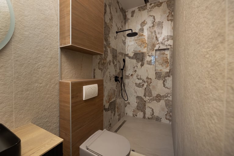 Modern bathroom interior with walk-in shower, toilet, wood cabinetry, and neutral beige tile walls